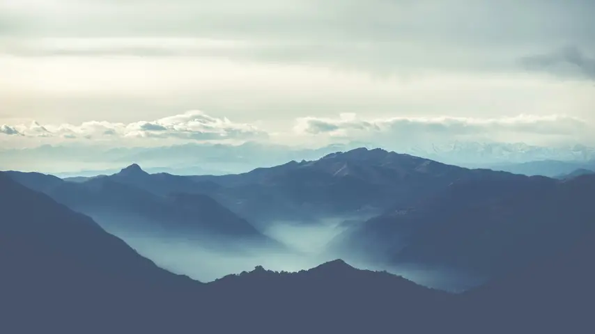 Black rocky mountains under a cloudy sky