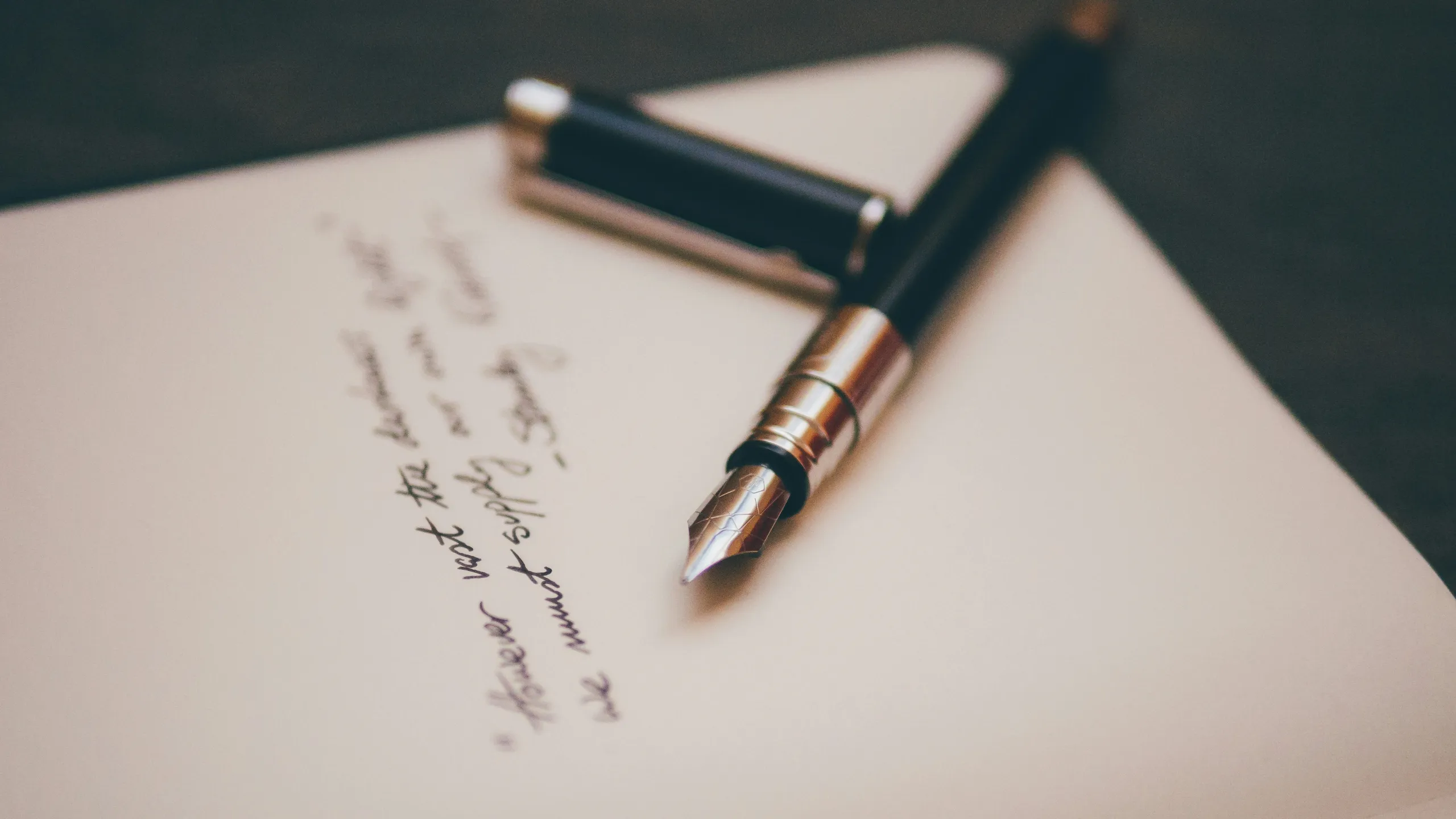 Closeup photo of a fountain pen resting on top of an notebook