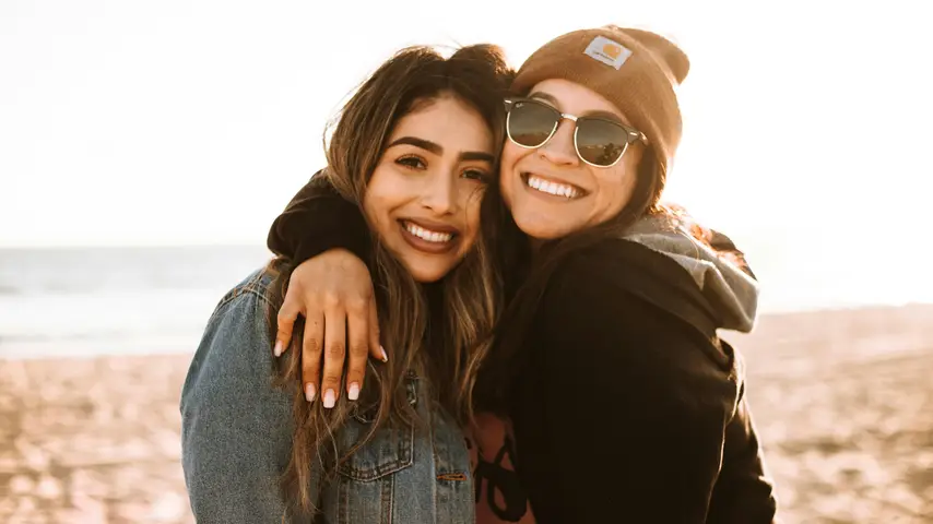 Two female friends smiling and hugging each other