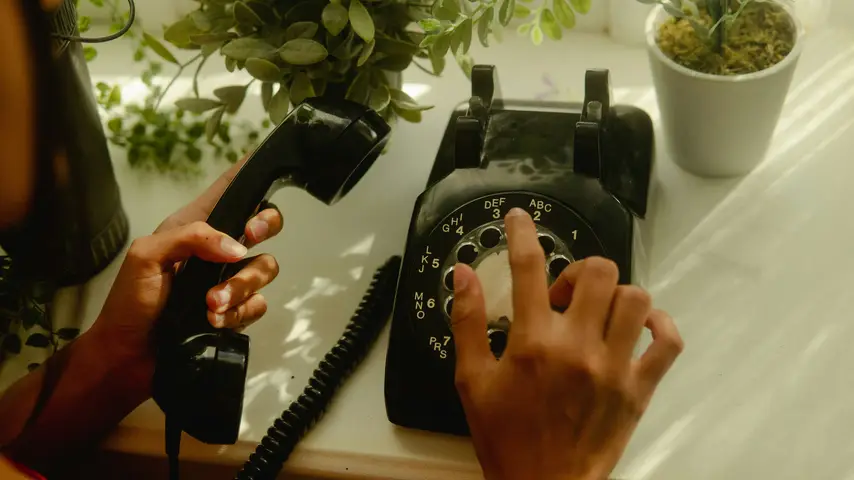 Person using a black rotary telephone