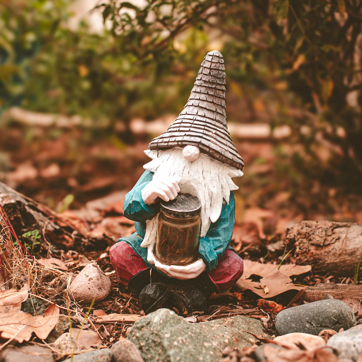 A bearded gnome seated on the ground in a garden